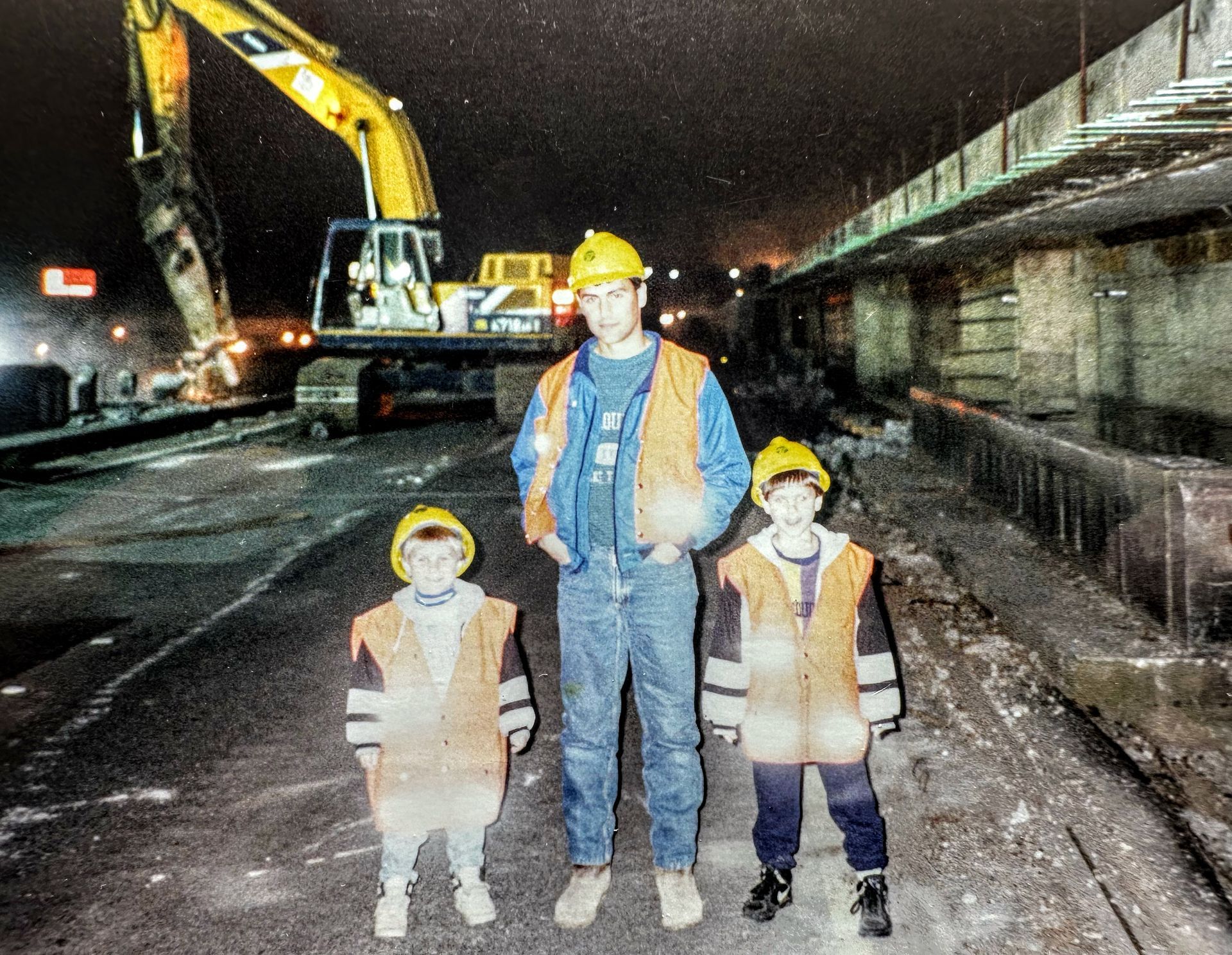 a man and two children are standing in front of a construction site at night