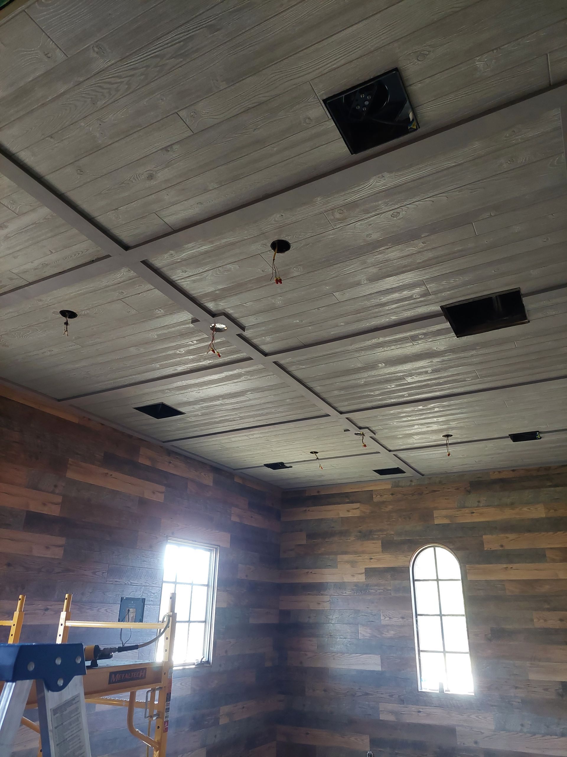 a room with wooden walls and a ceiling with holes in it .