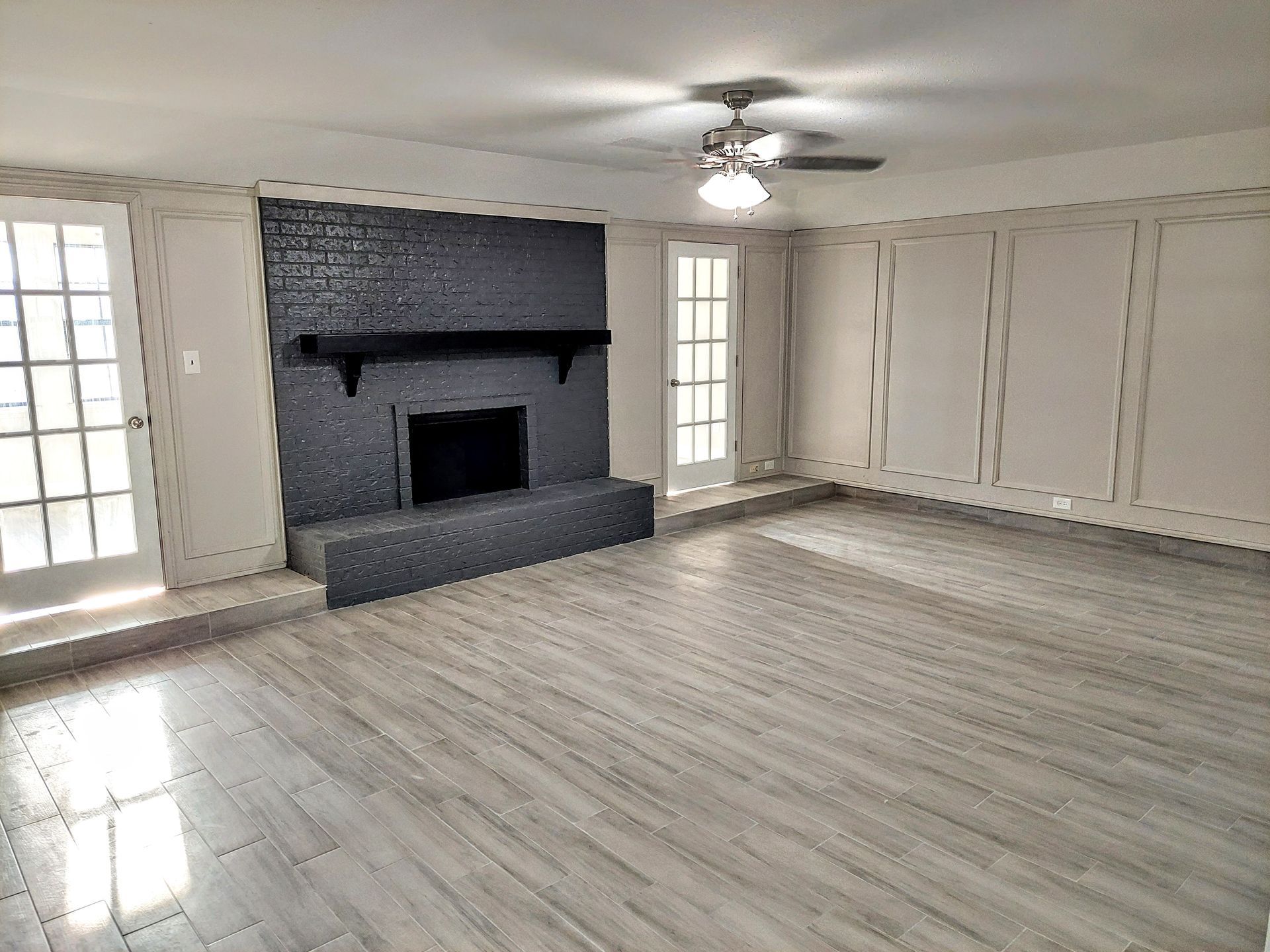an empty living room with a fireplace and a ceiling fan .