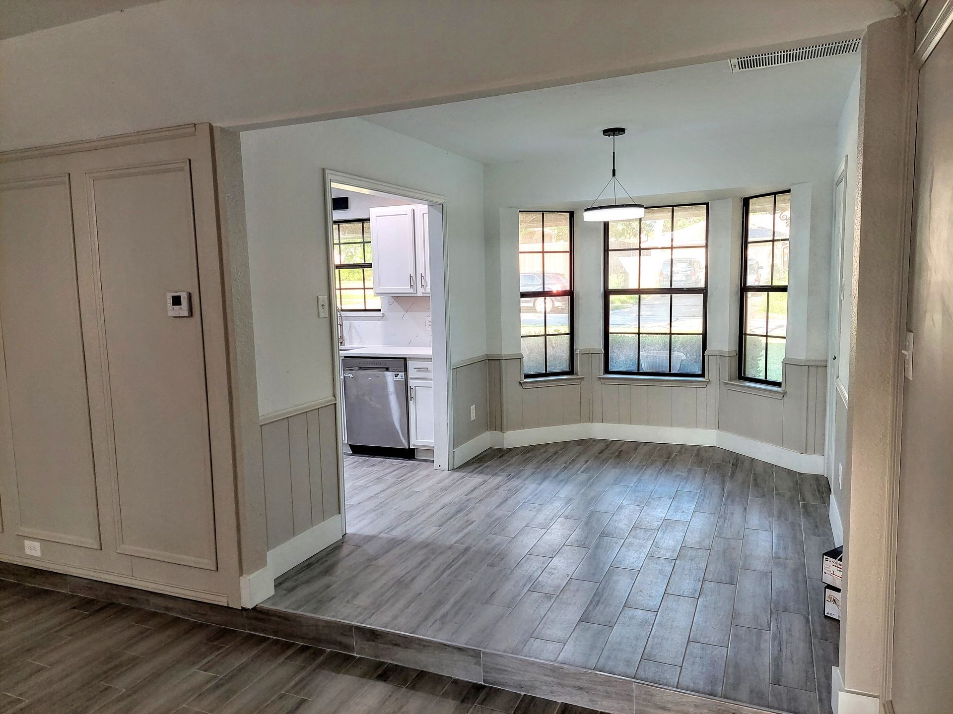 an empty dining room with hardwood floors and a bay window .