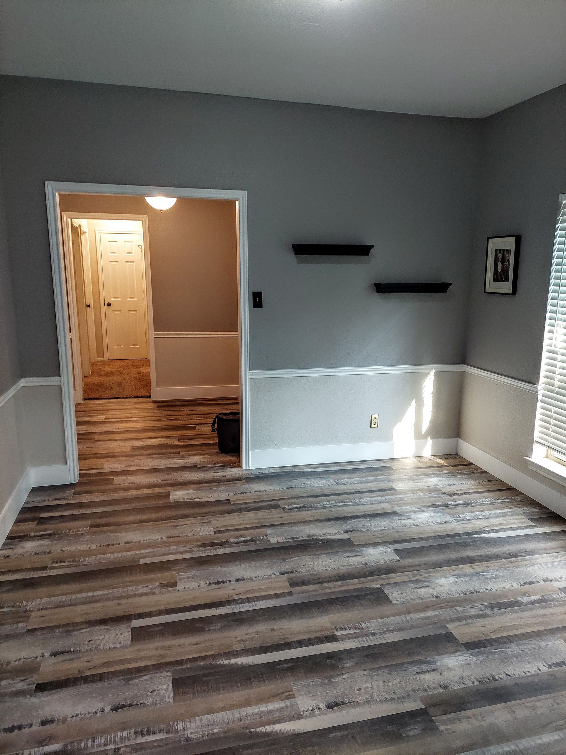 an empty living room with wooden floors and gray walls .