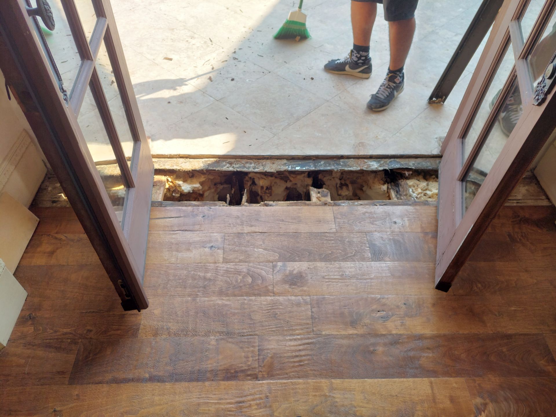 a person is standing in a doorway with a broom