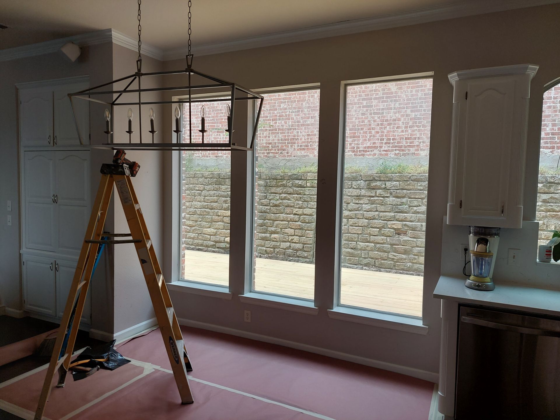 a wooden ladder is sitting in a room with a lot of windows .
