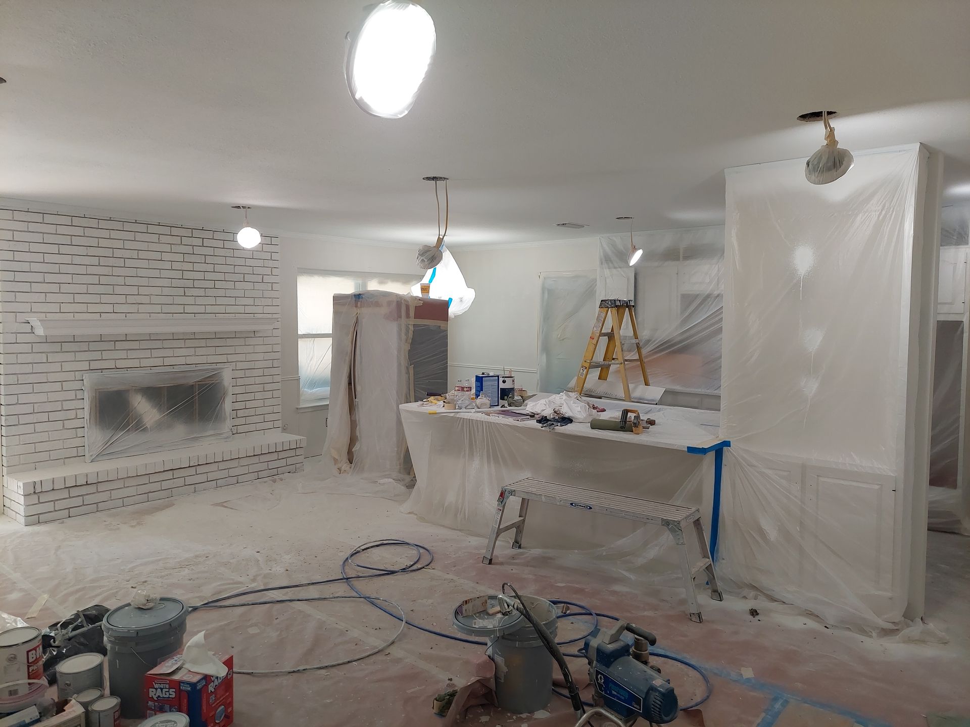 a living room is being painted white and covered in plastic .