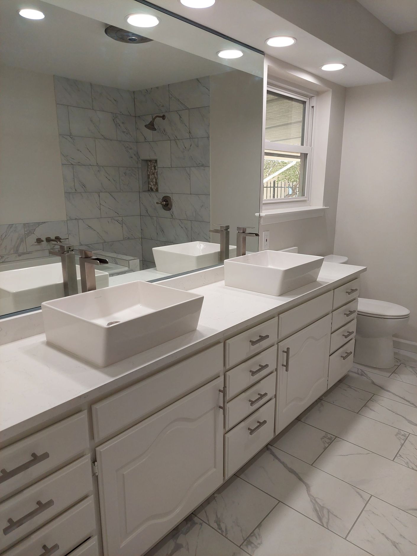 a bathroom with two sinks , a toilet , and a large mirror .