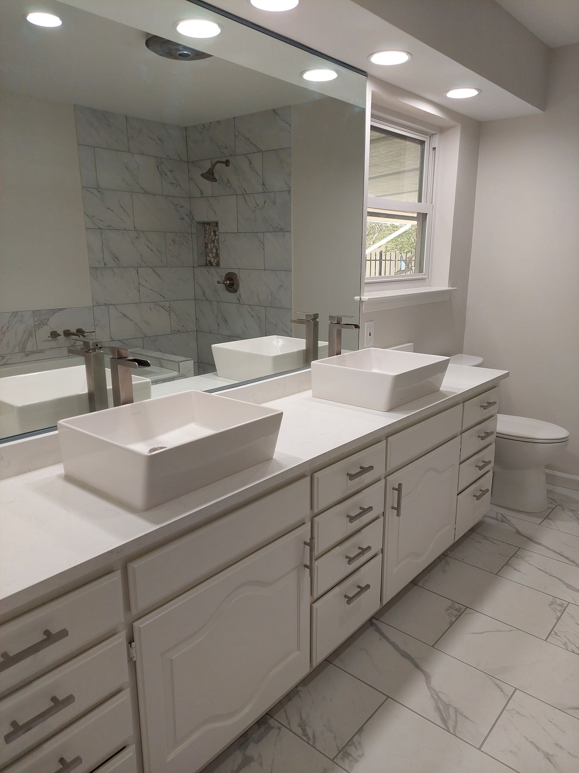 a bathroom with two sinks , a toilet , and a large mirror .