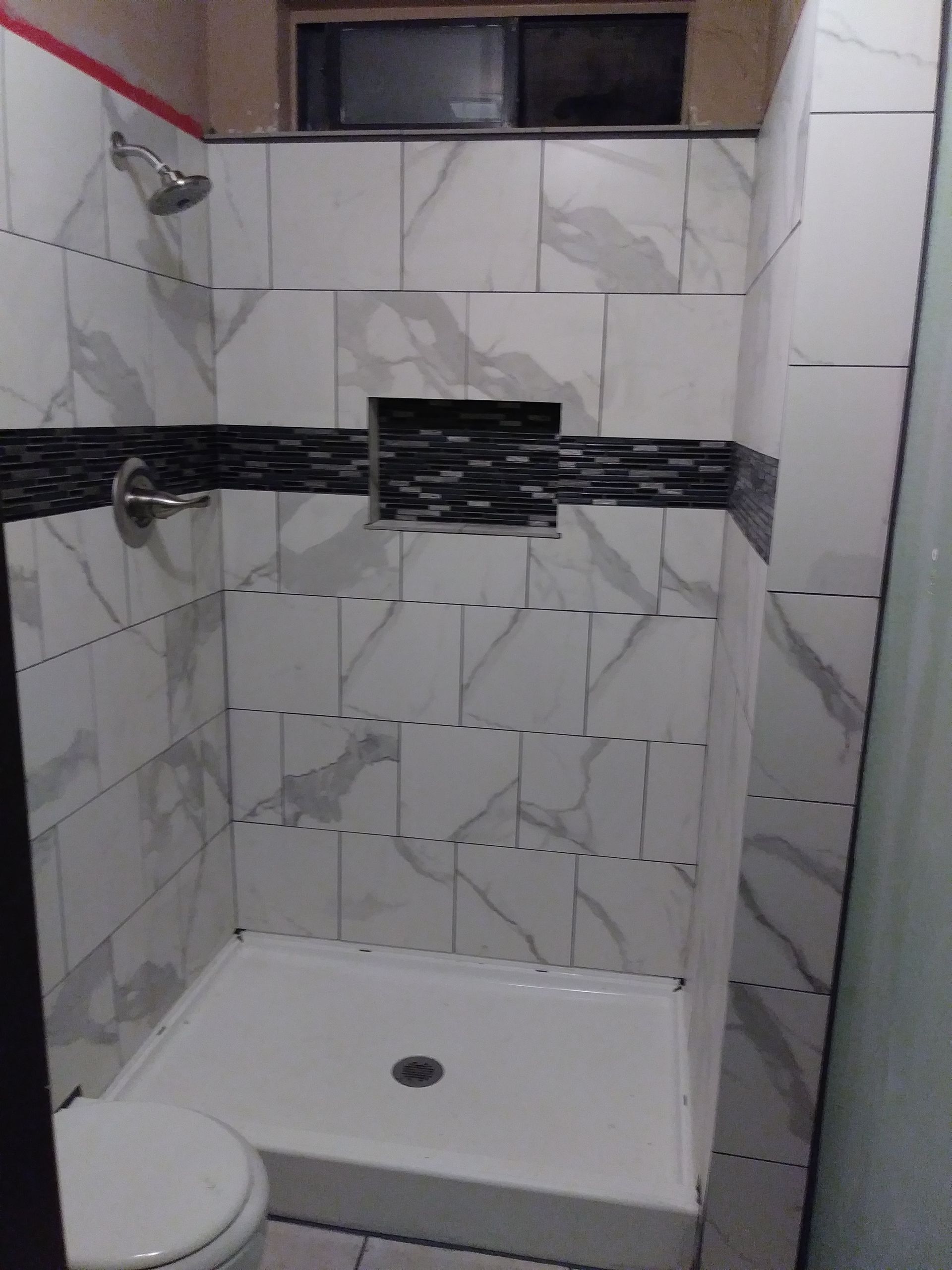 a bathroom with a toilet , shower and marble tiles .