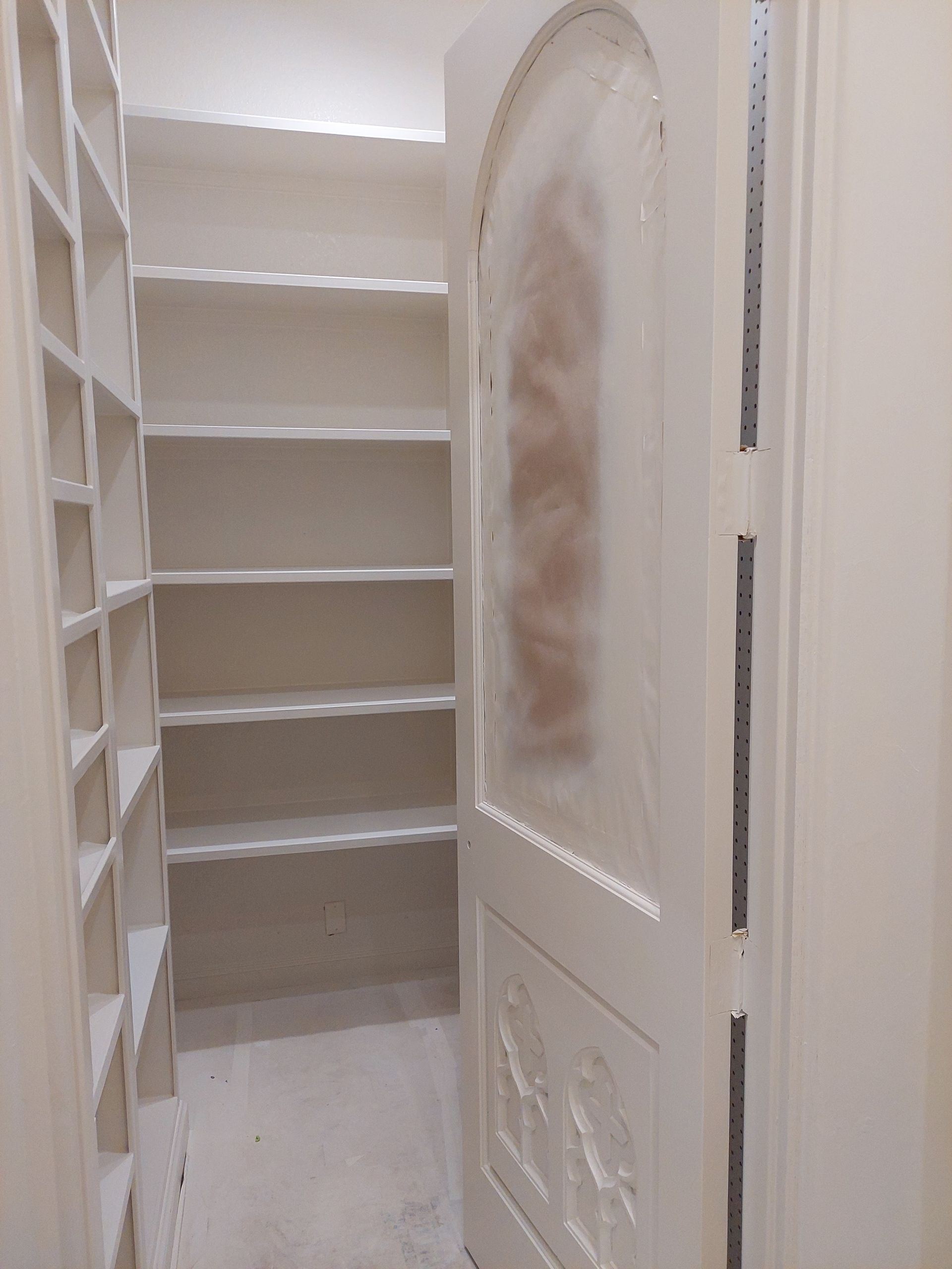 a walk in closet with shelves and a door .