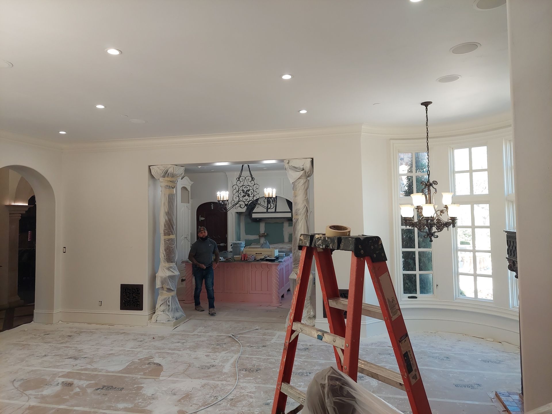 a man is standing in a room with a ladder in front of him .