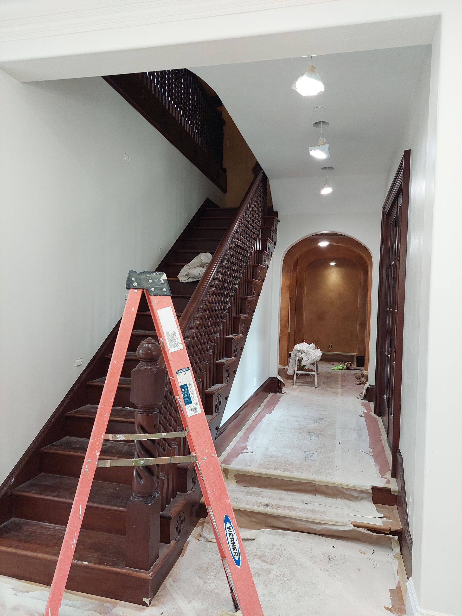 a ladder is leaning against a wooden staircase in a hallway .