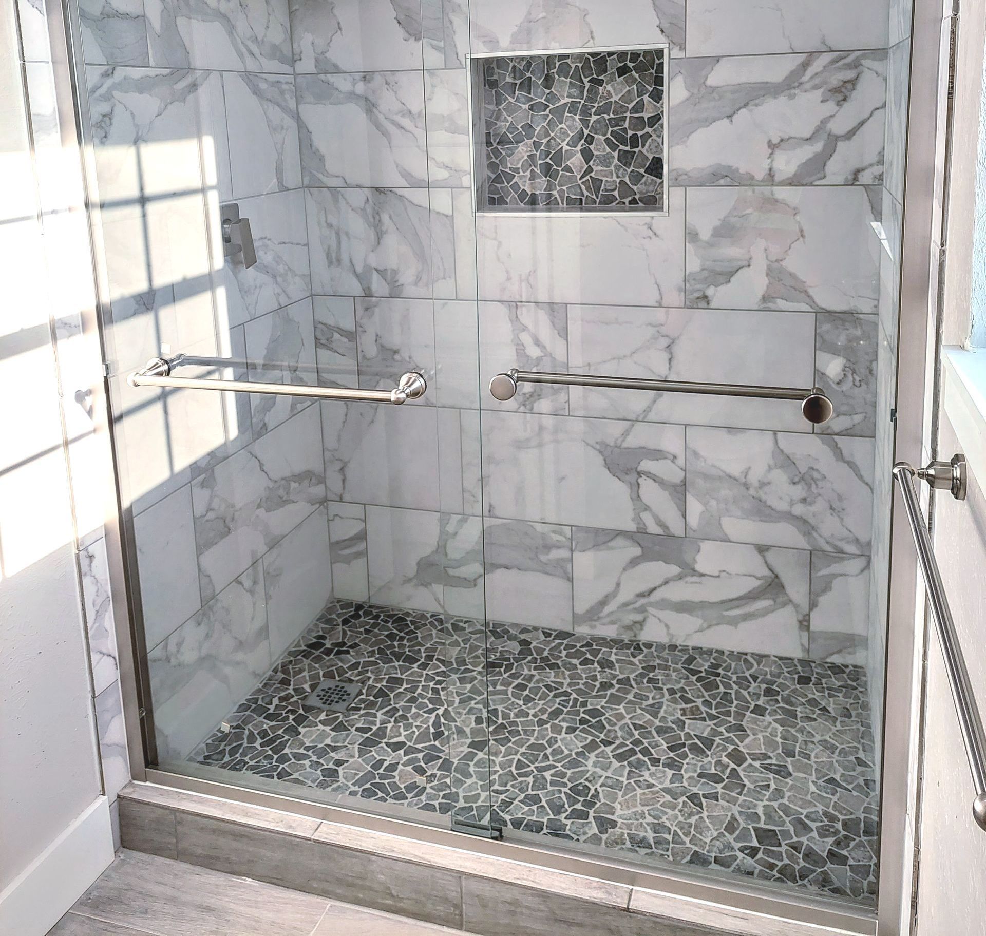 a shower with marble tiles and a glass door