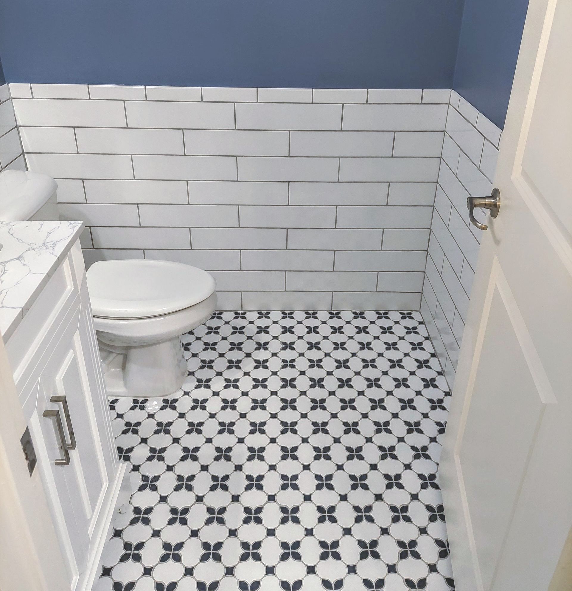 a bathroom with a toilet , sink , and black and white tile floor .