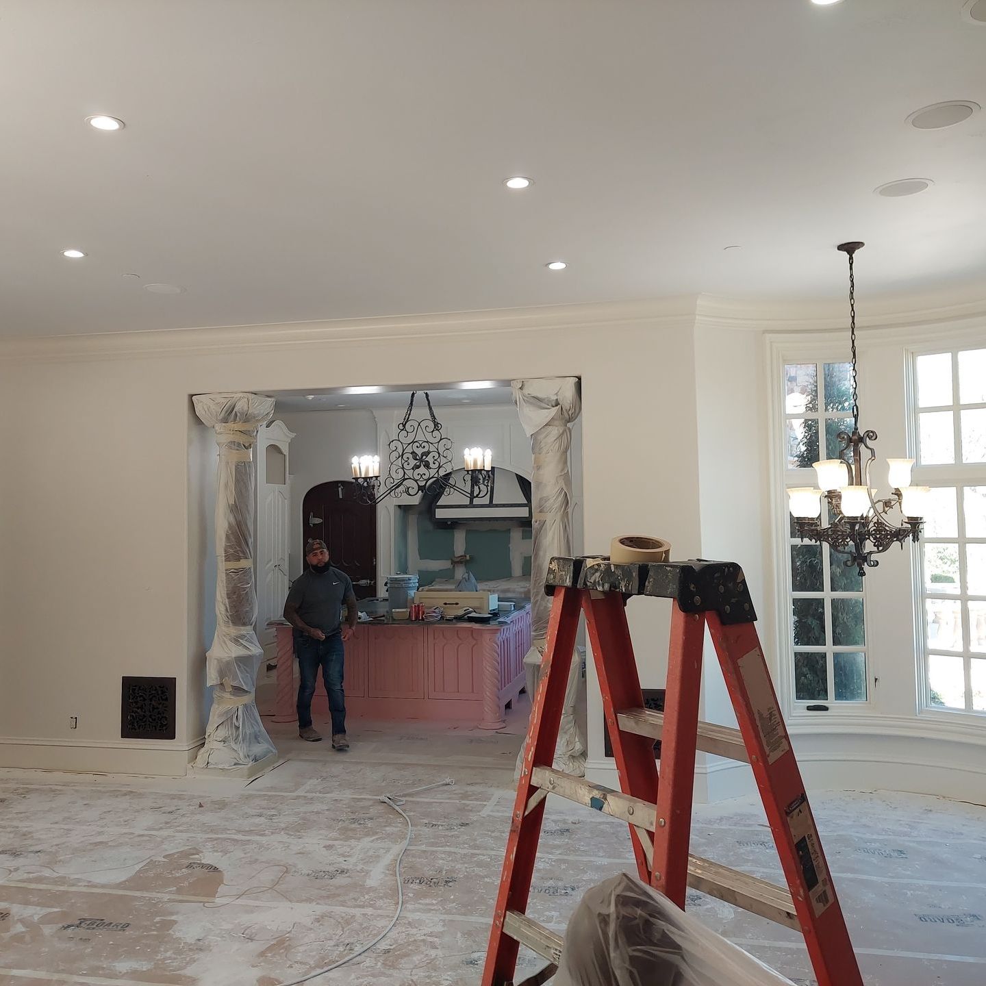 a man is standing in a room with a ladder in front of him .