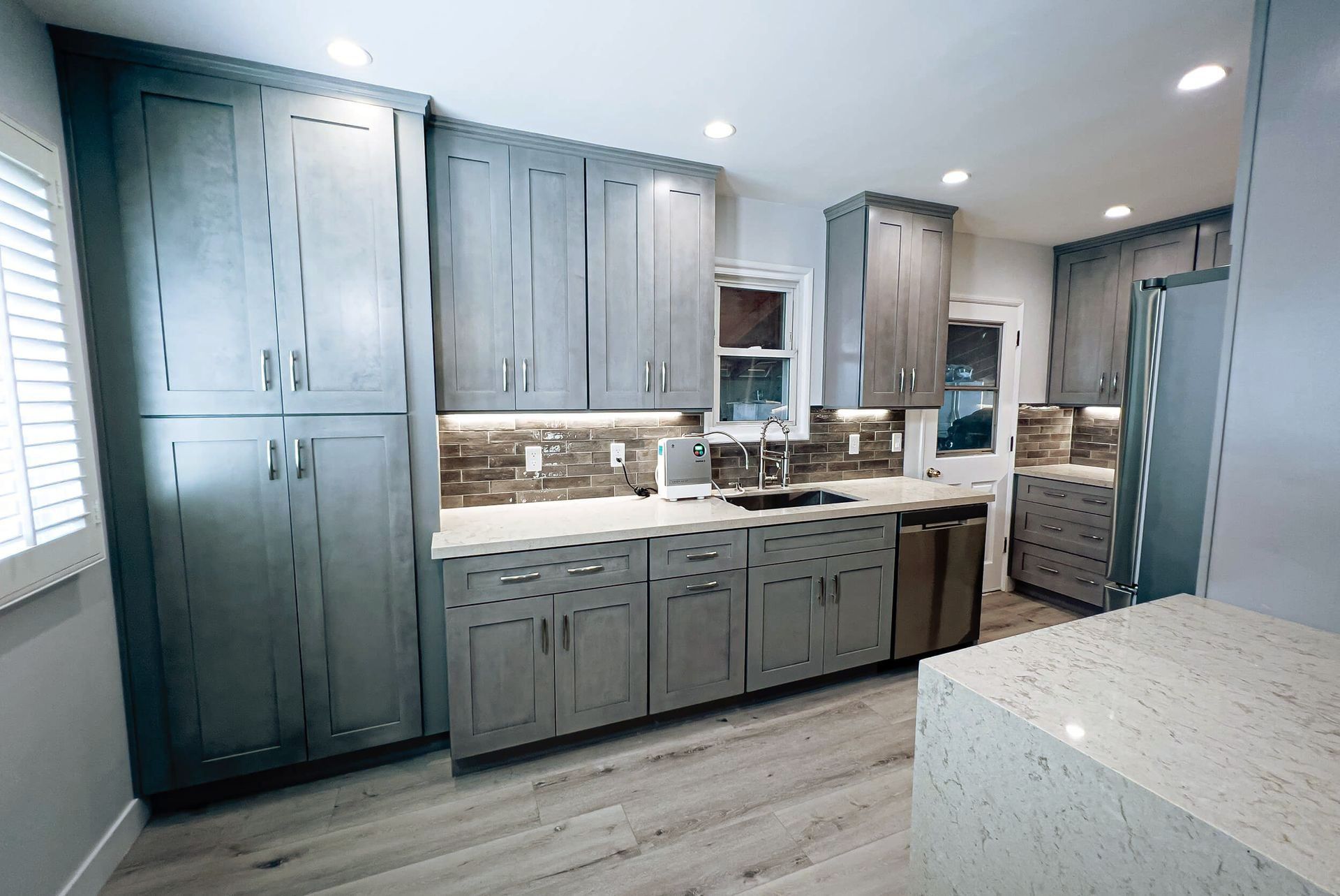 a kitchen with gray cabinets and white counter tops