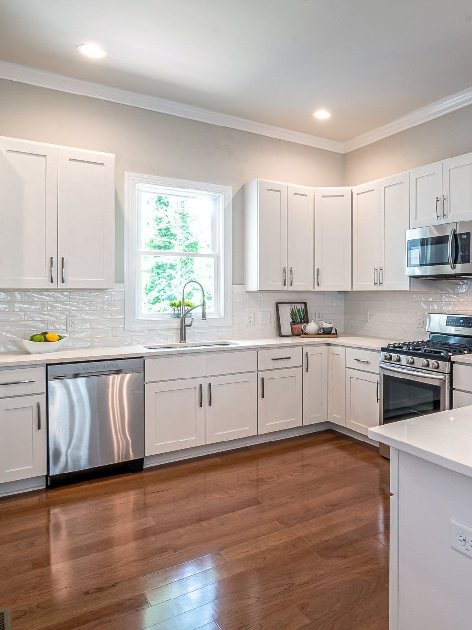 a kitchen with white cabinets , stainless steel appliances , and hardwood floors .