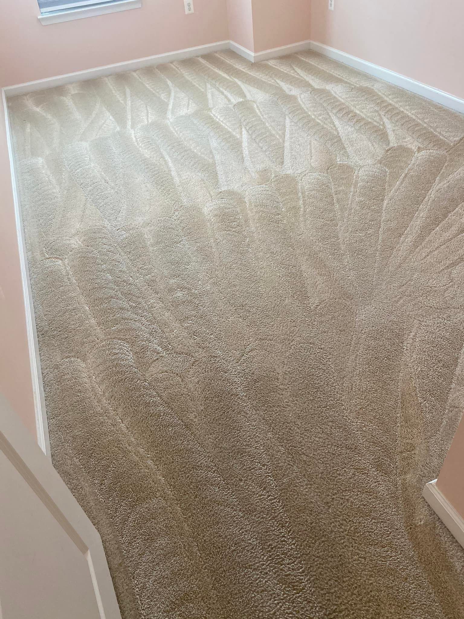 Beige carpeted room, with a pattern of alternating directions. White baseboards, pink walls.