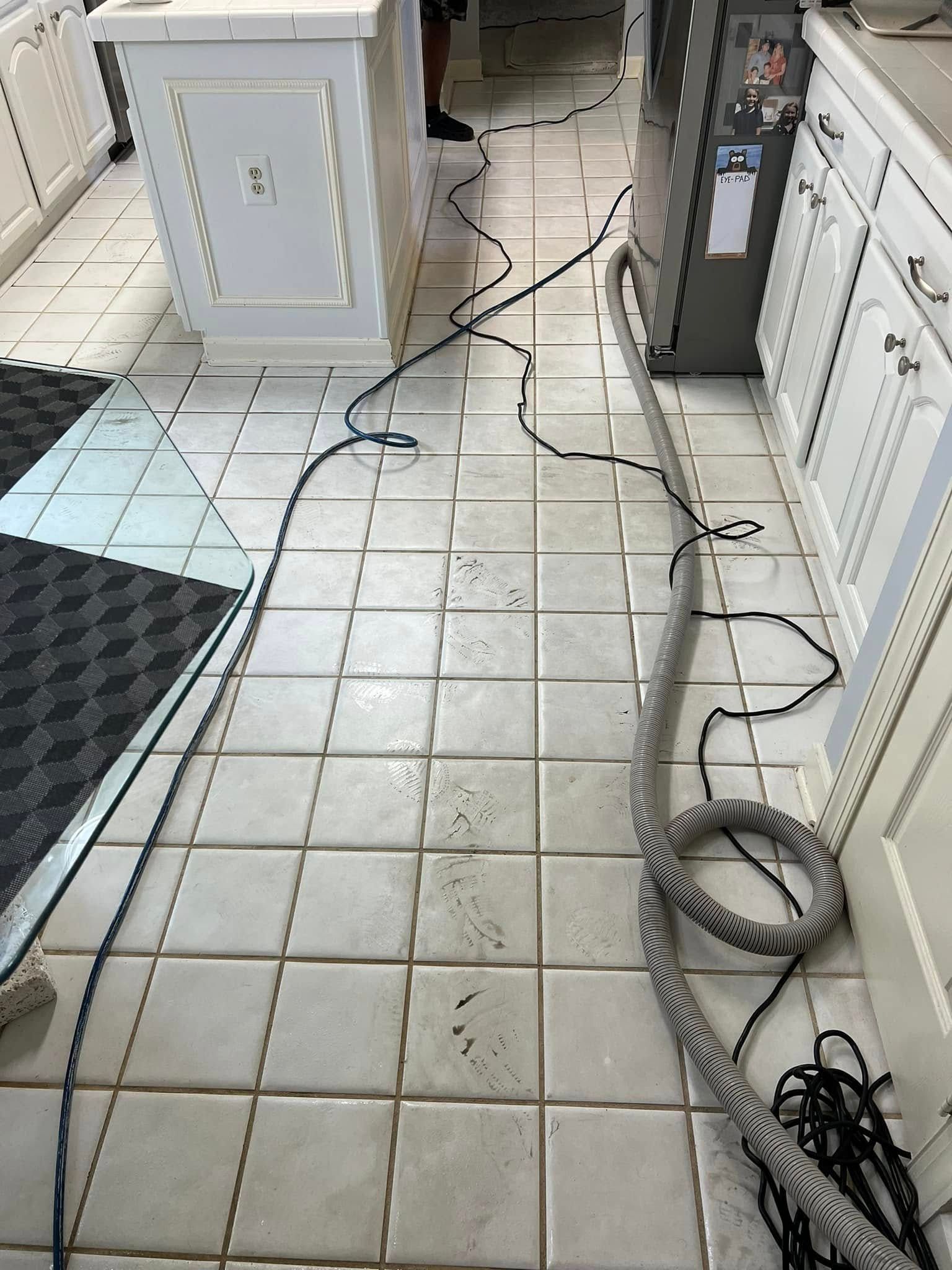 Kitchen with electrical cords on the tiled floor, running from a machine to an island and a cabinet.