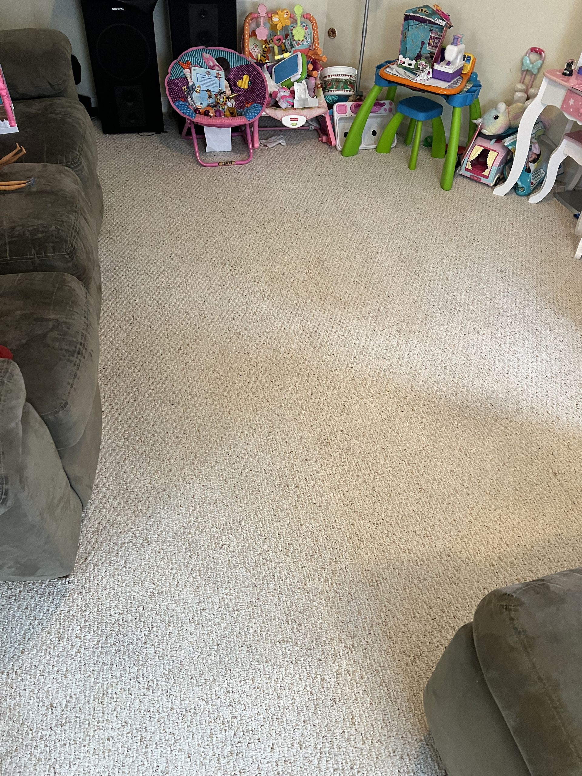 Beige carpet with wrinkles, surrounded by furniture and children's toys in a living room.