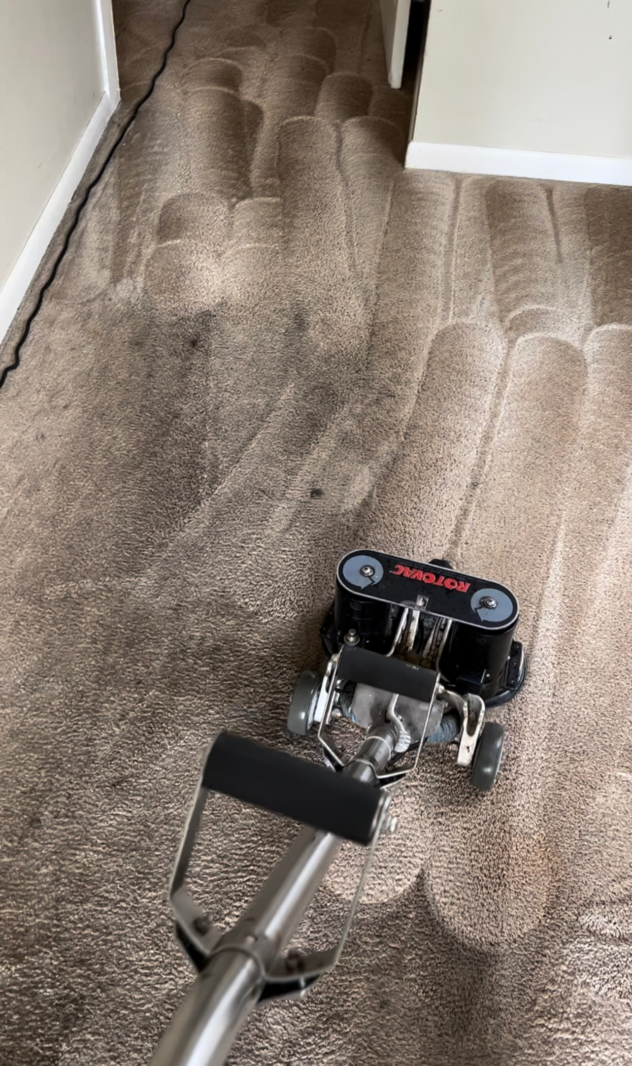 Carpet cleaning machine on a dirty, brown carpet; a door frame is visible.