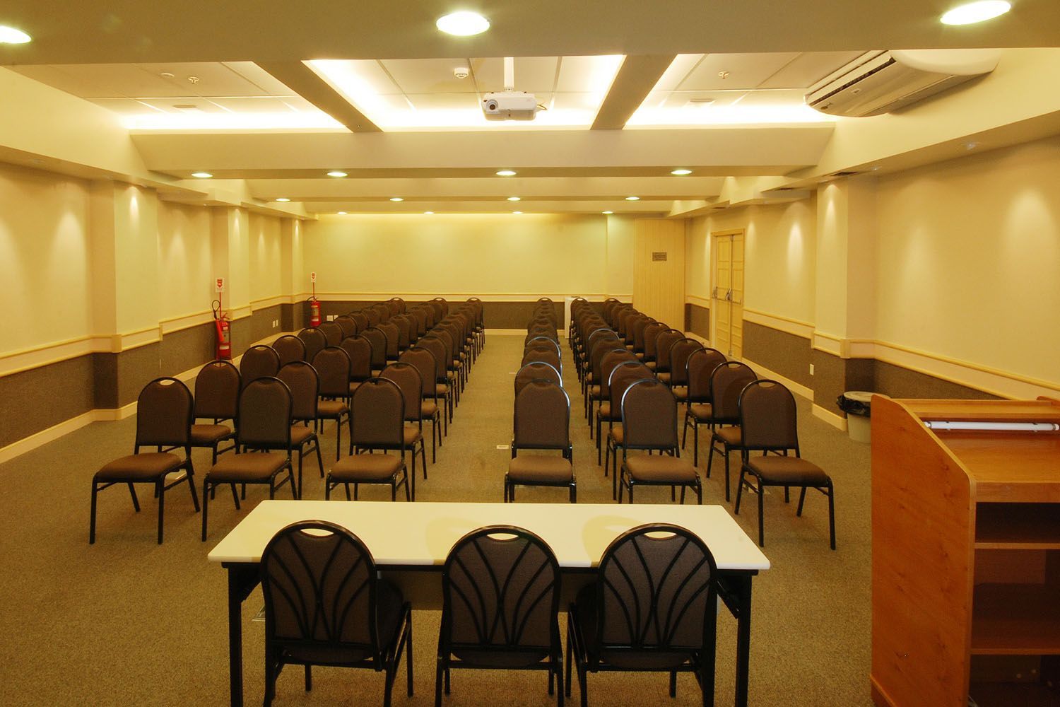 Uma sala de conferências com mesas e cadeiras e um pódio