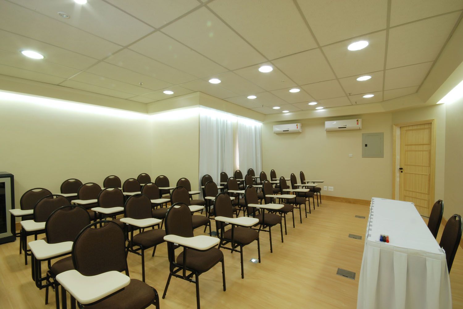 Uma sala de conferências com fileiras de cadeiras e uma mesa
