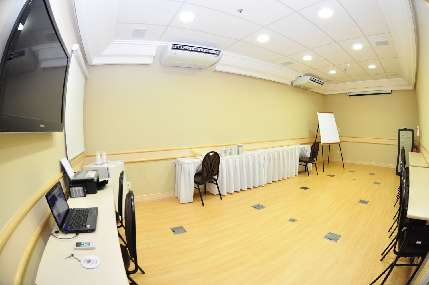 Uma sala de conferências com mesas e cadeiras e um laptop em uma mesa