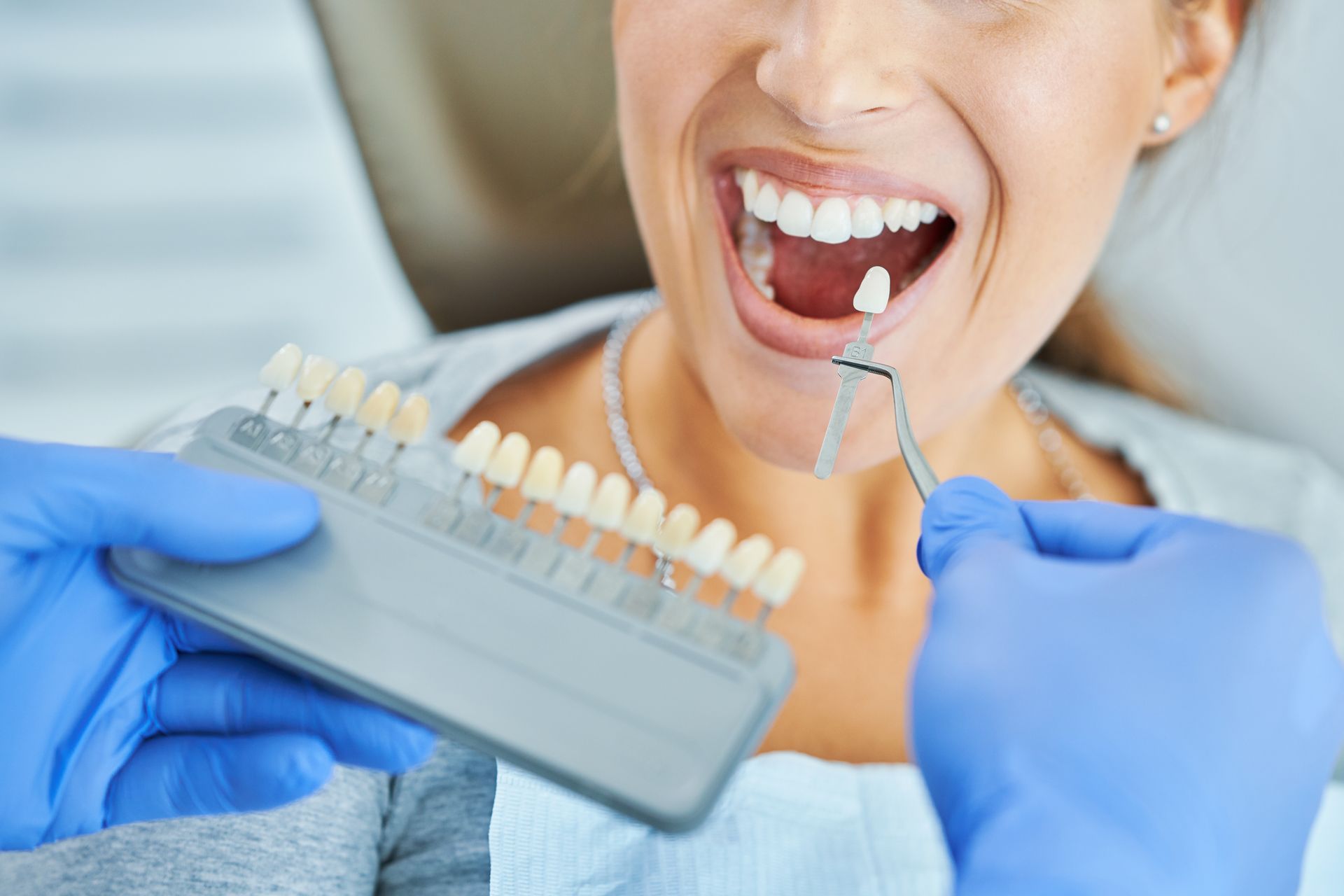 Dentist matching porcelain veneer shade for a cosmetic dental treatment in Newtown.