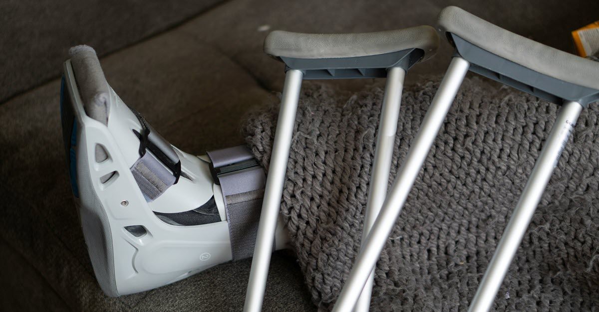 Broken white crutches leaning against a sofa on a carpeted floor