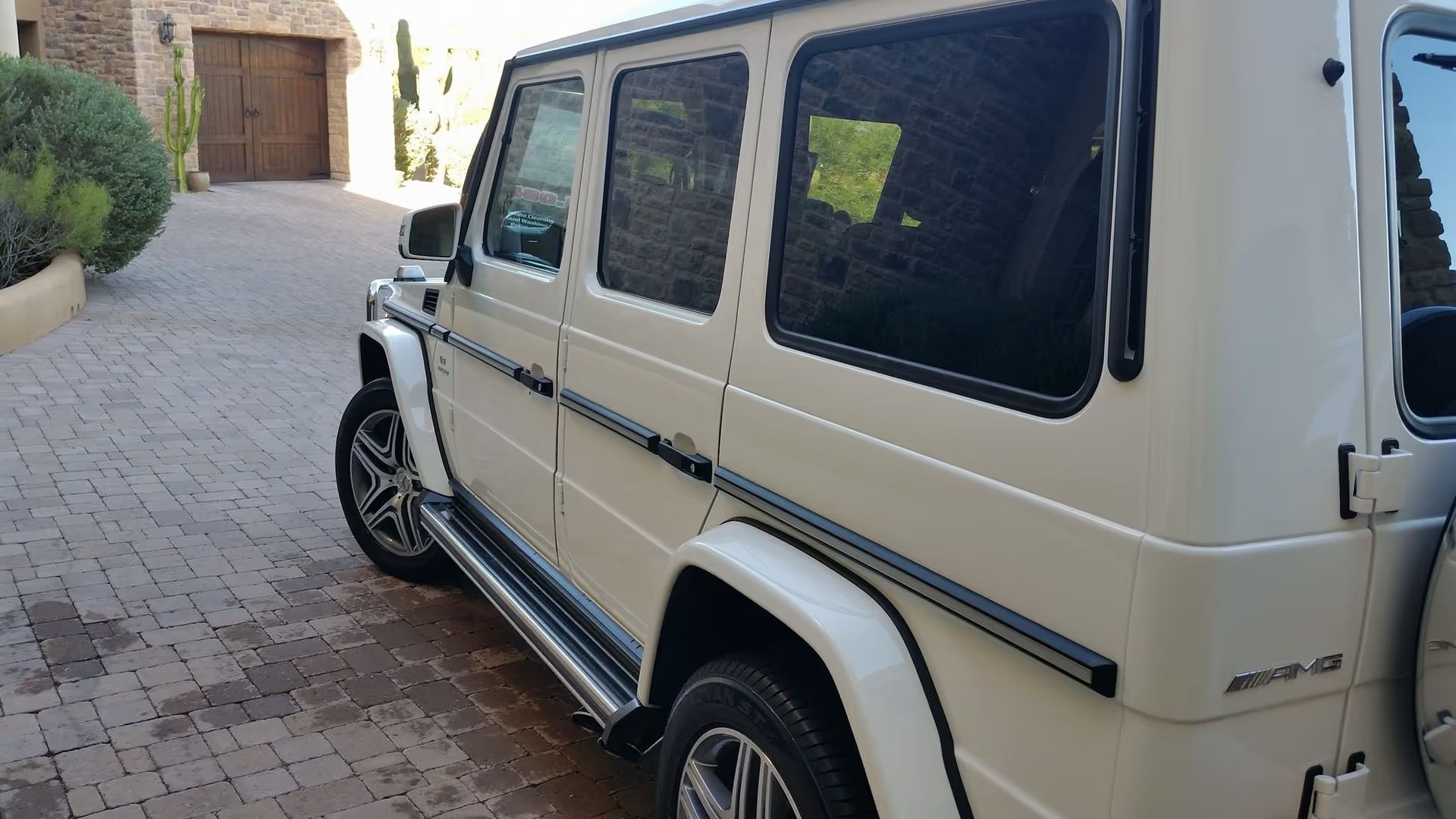 White SUV parked on a cobblestone driveway beside a building wall