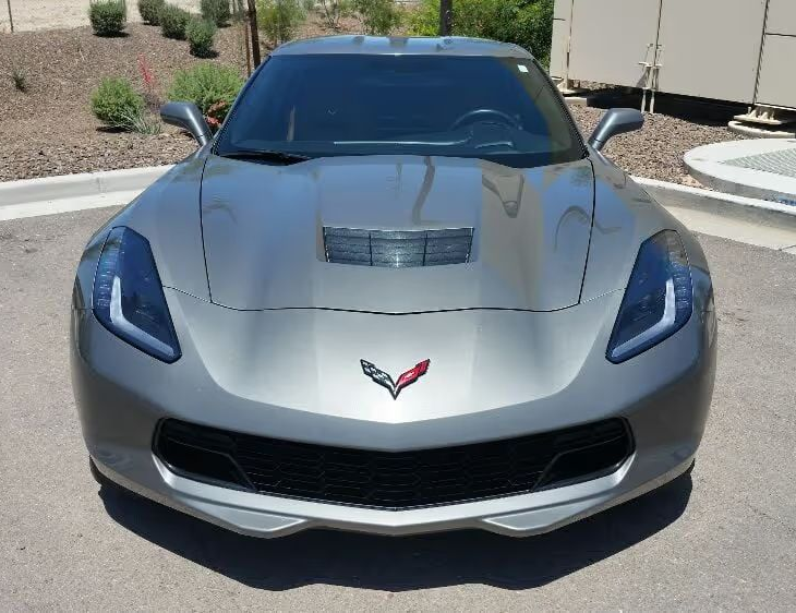Silver Chevrolet Corvette parked outdoors on a sunny day, front view