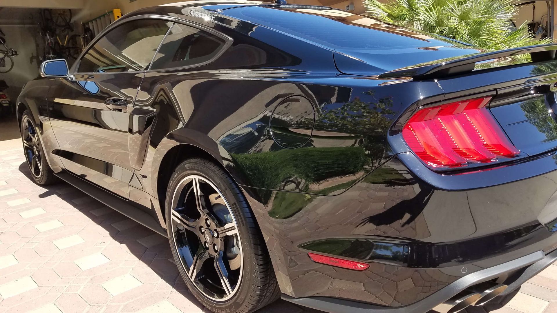 Black sports coupe parked outdoors, rear three-quarter view, with glossy paint and red taillights.