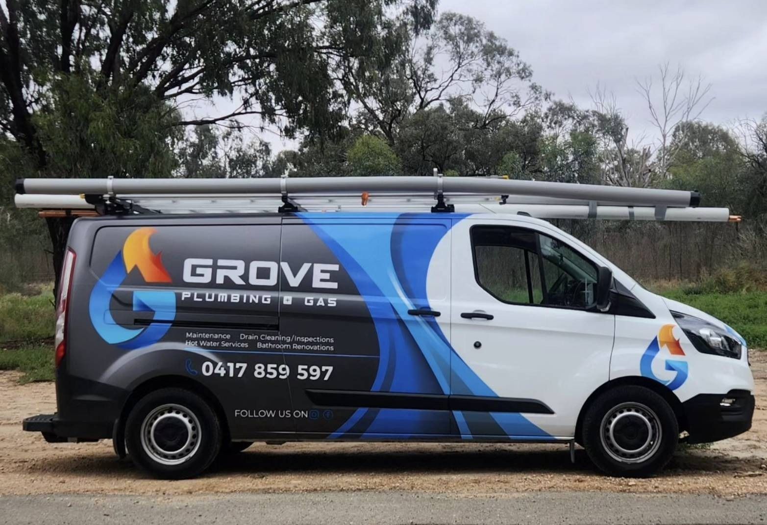 White GROVE service van with blue/orange graphics and ladders on roof, parked roadside.
