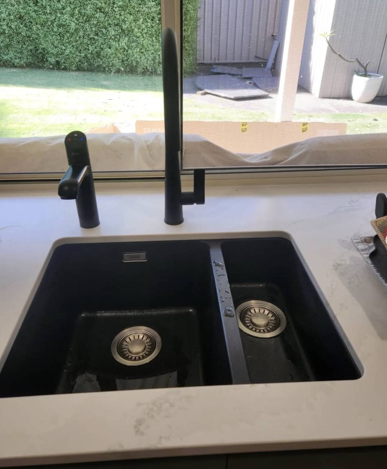 Modern black double kitchen sink with faucet and stone countertop in a bright kitchen.