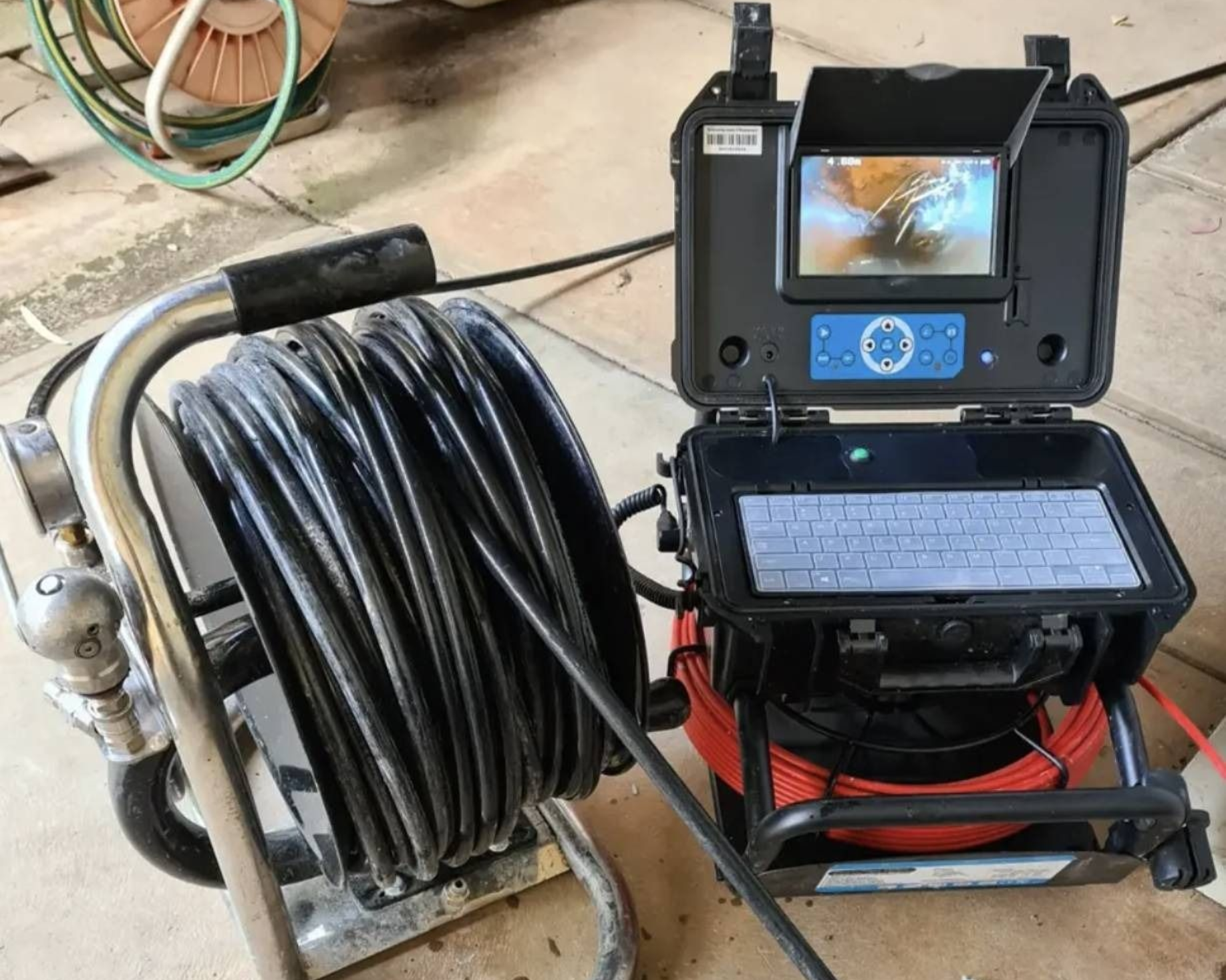 Pipe inspection camera with monitor and coiled cable on a wheeled cart in a workshop