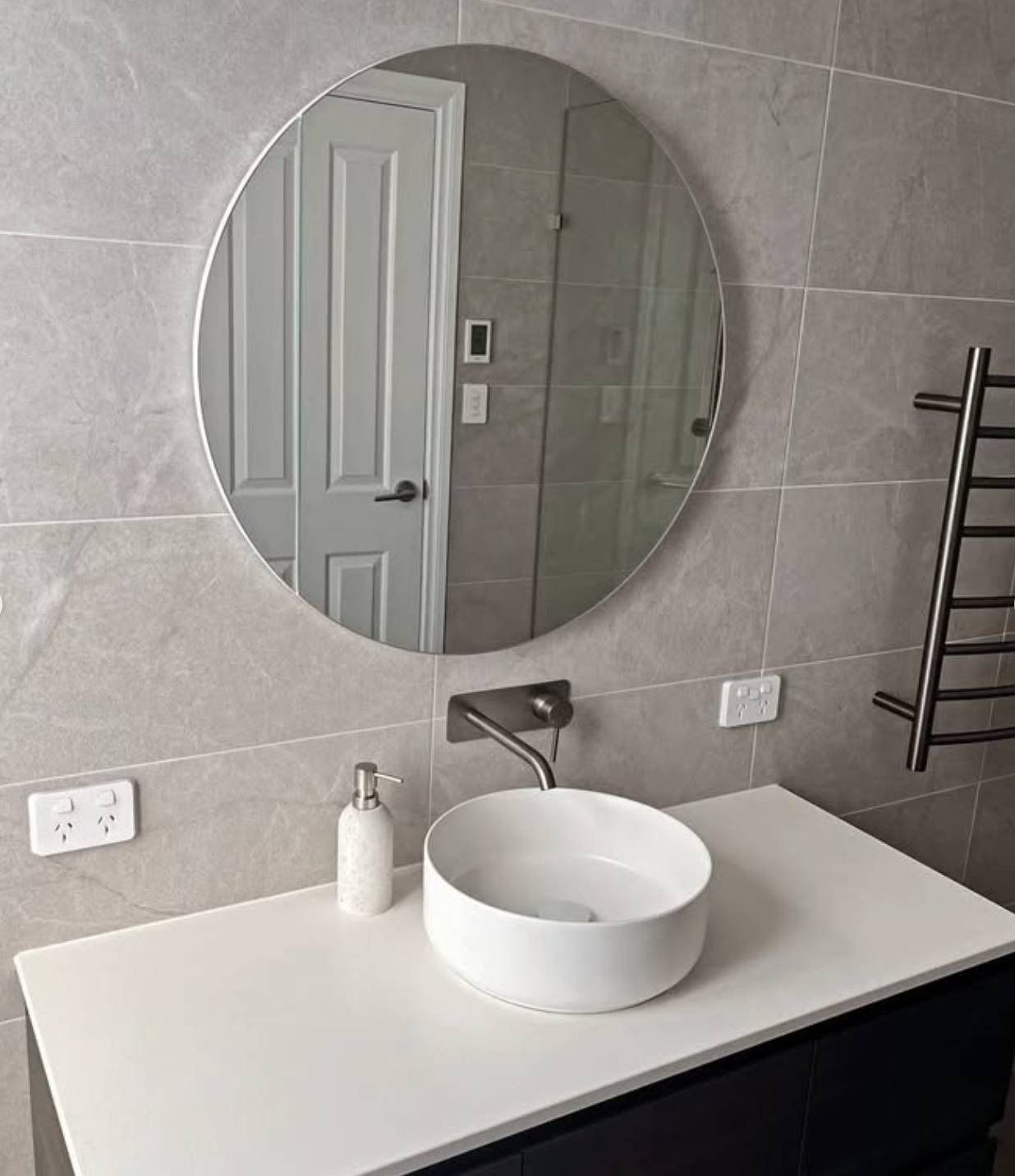 Modern bathroom sink with round mirror and white countertop vanity