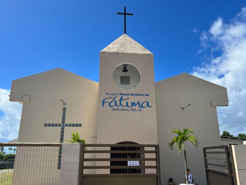 Church with a cross on top, "Nossa Senhora de Fátima" sign, blue sky background.