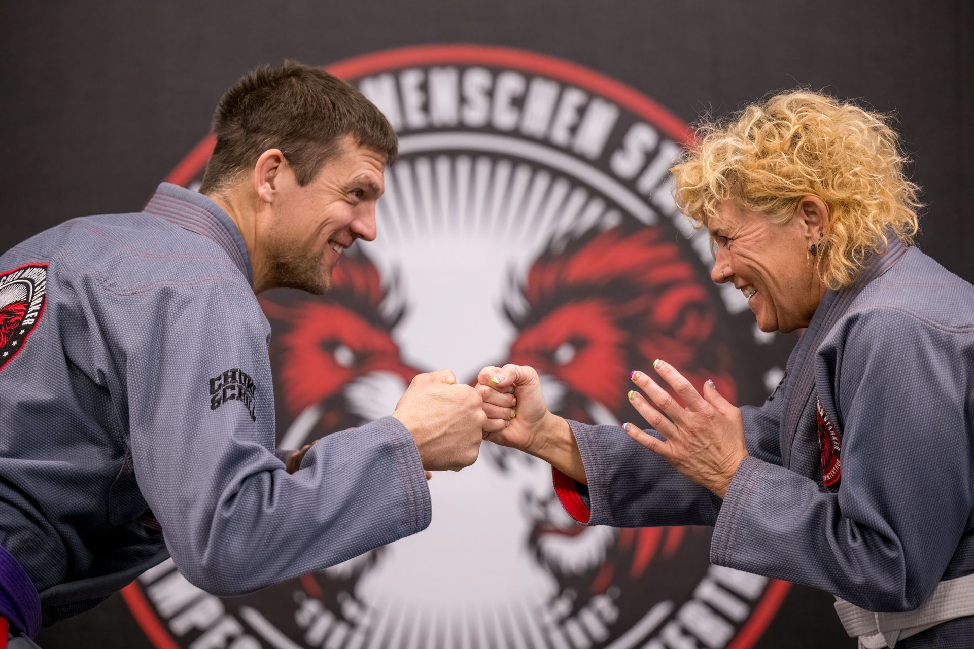 Ein Mann und eine Frau geben sich vor einem Löwenlogo die Hand.
