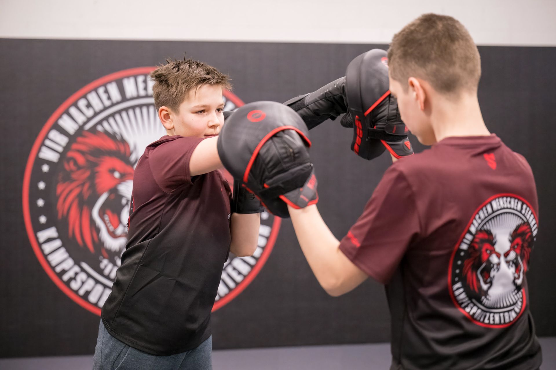 Zwei junge Jungen üben in einem Kampfsportzentrum auf einer Matte.