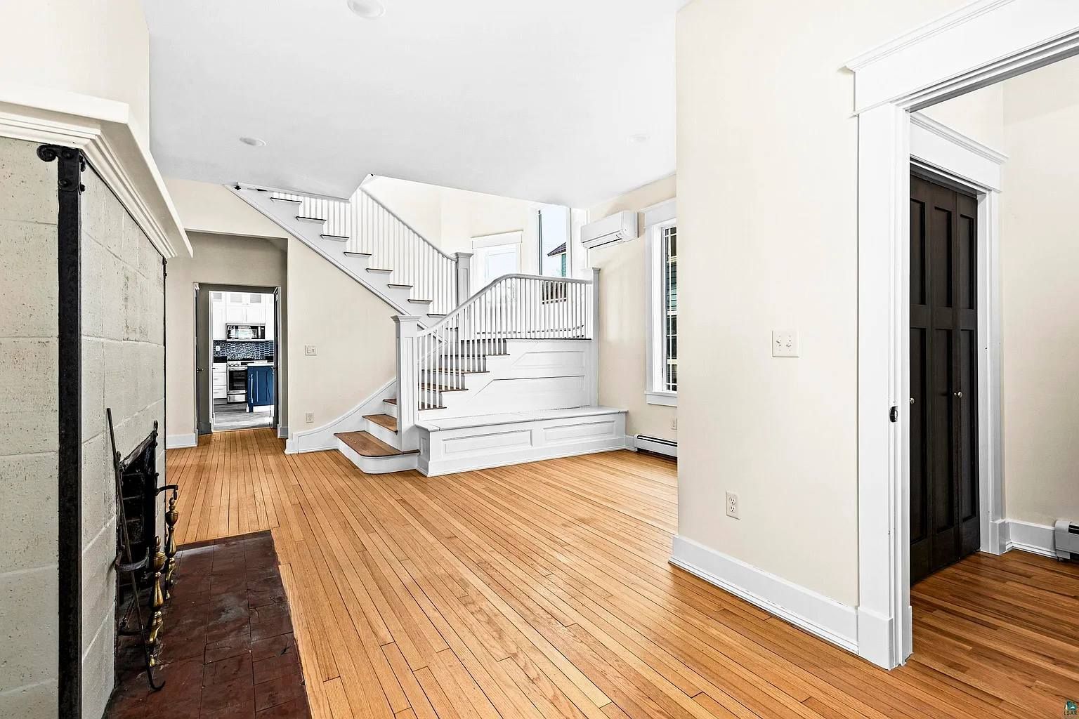 A living room with hardwood floors , a fireplace and stairs.