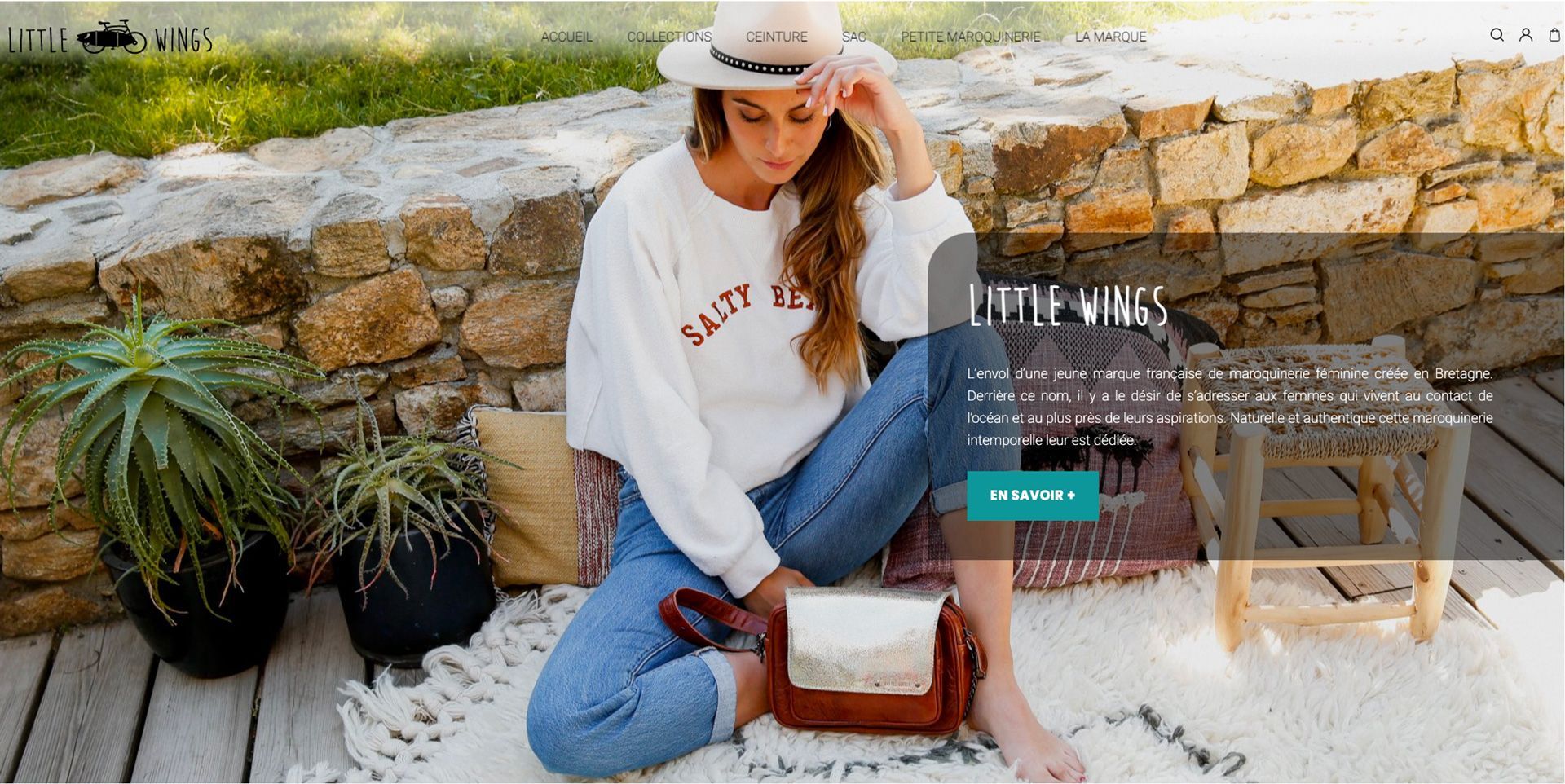 Une femme est assise sur le sol portant un chapeau et un pull.