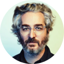 A man with gray hair and beard wearing glasses, looking directly at the camera.