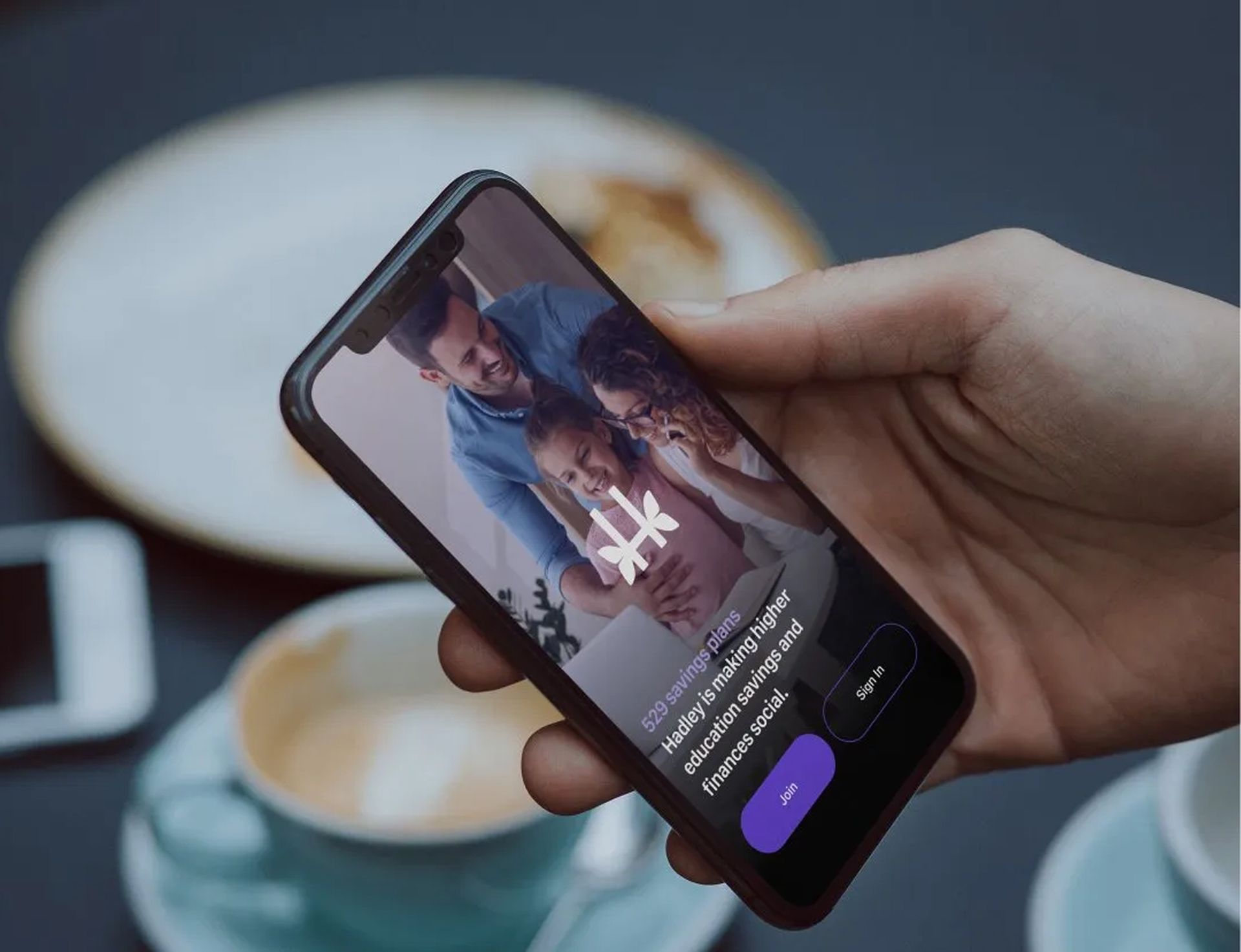 Hand holding a smartphone displaying a family celebrating. 
