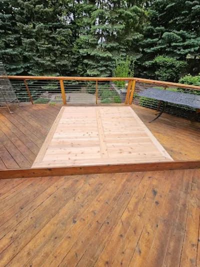 A wooden deck featuring a light-colored rectangular wood-patch repair surrounded by original stained-brown decking.