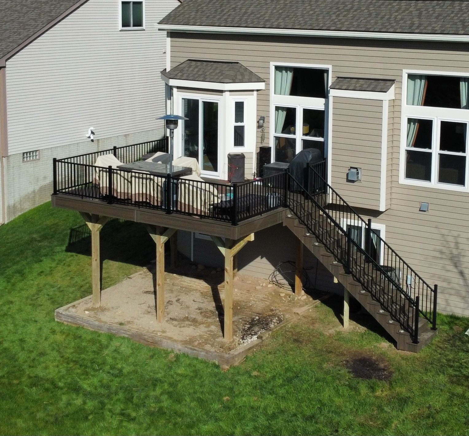 A partially constructed wooden deck featuring bare joists on the left and finished light-colored wood planks on the right.