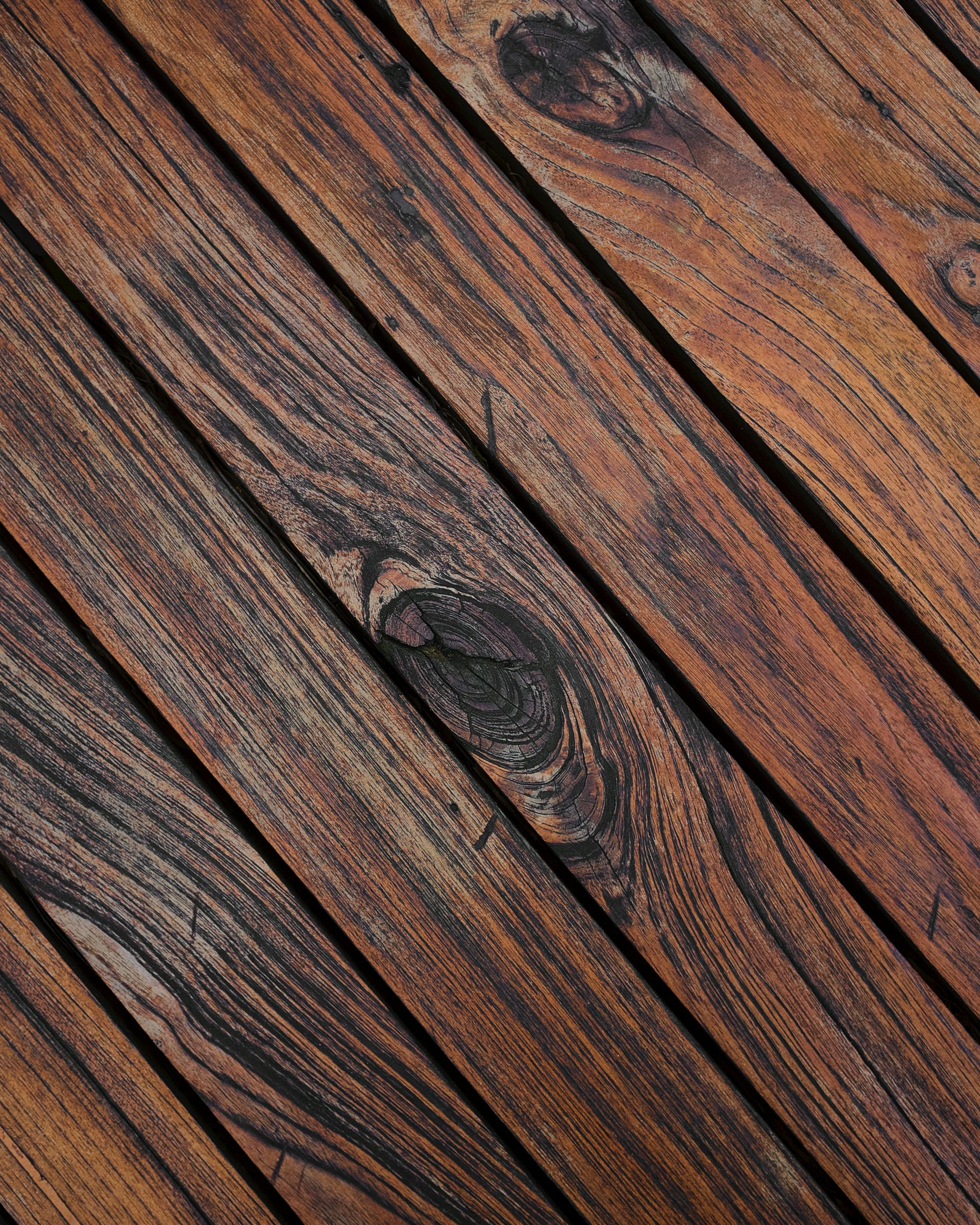 Dark brown wooden planks arranged diagonally, featuring prominent wood grain and knots.