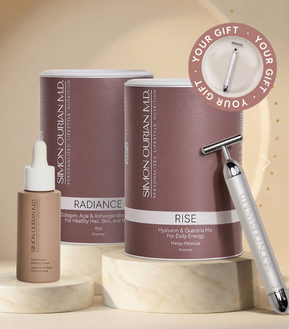 Hautpflege-Geschenkset mit lilafarbenen Tuben, Tropfflasche, Rasierer und roségoldenem „Your Gift“-Anstecker auf beigefarbenem Hintergrund