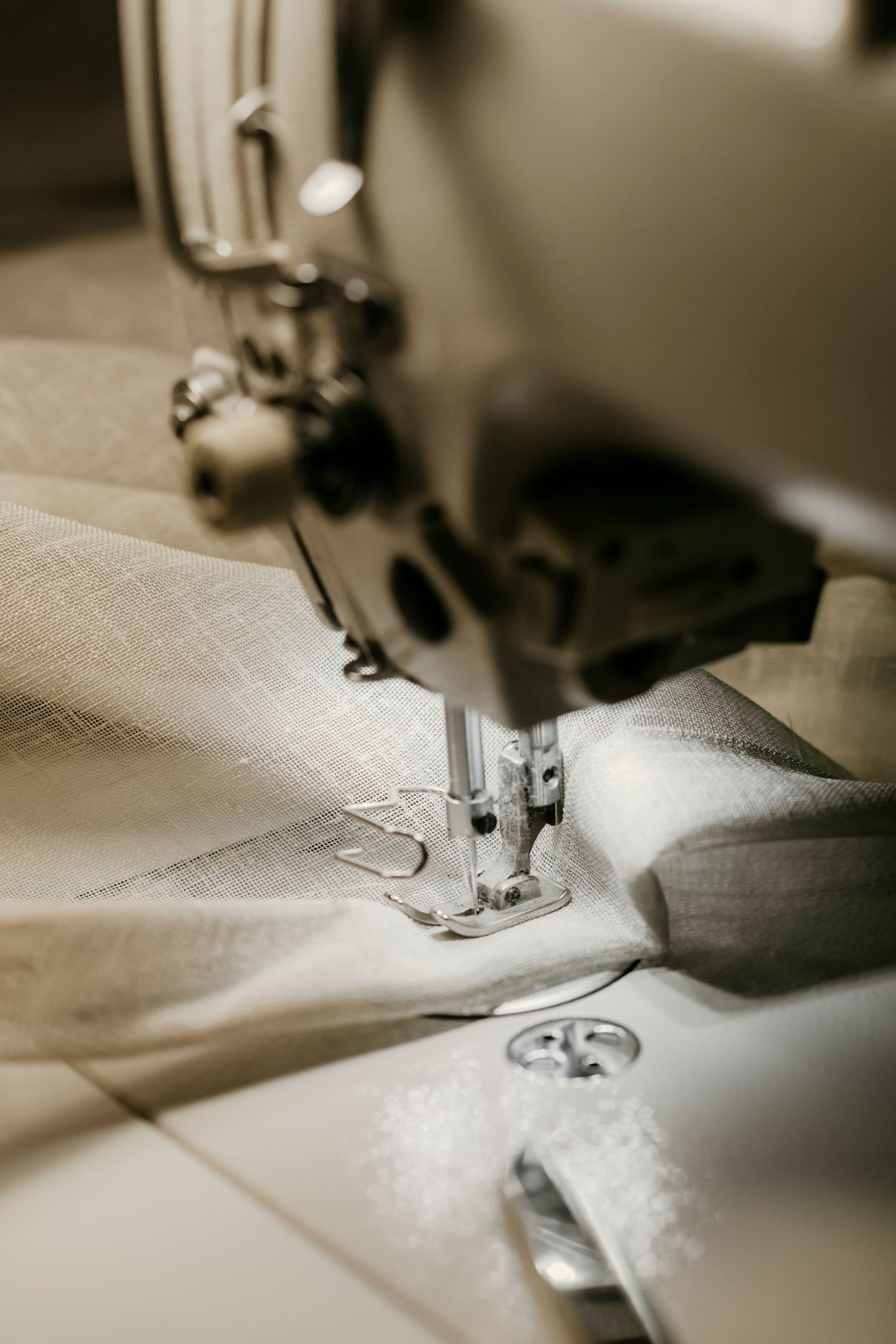 Close-up of a sewing machine stitching white fabric with a textured pattern — Curtain Concepts in Dunbible, NSW