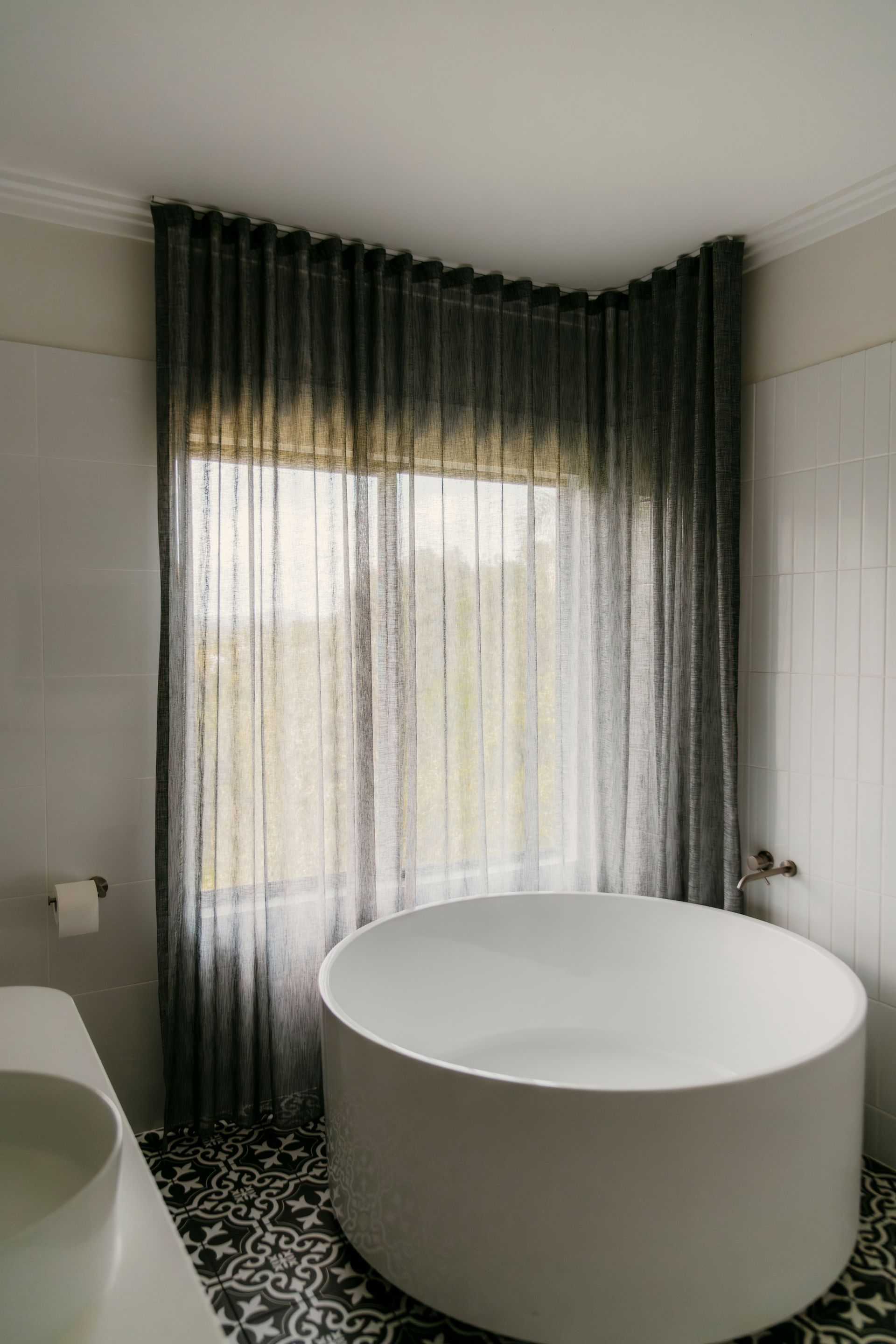 Modern bathroom with a freestanding tub and floor-to-ceiling sheer gray curtains