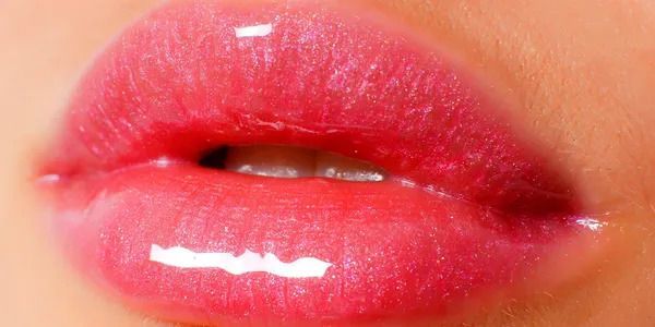 Close-up of glossy pink lips slightly parted, showing bright red lipstick and shine
