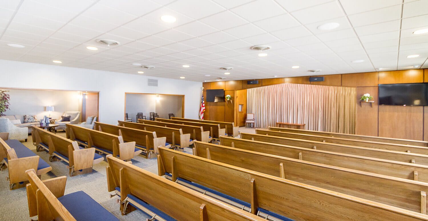 There are rows of wooden benches in a church.